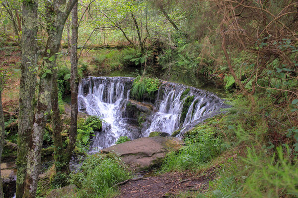 there is a water fall in the middle of the mountain woods that is called Pozo da Ferida