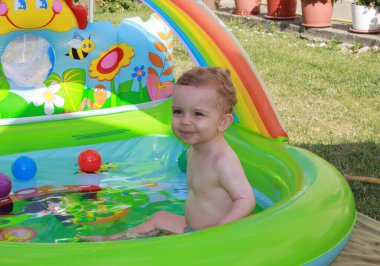 my one year old son enjoying his bath in the pool in his grandpas
