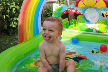 my one year old son enjoys playing in the plastic pool in his granpas