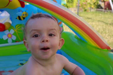 this baby is enjoying a bath in a plastic pool placed in the garden