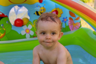 my son having a bath in the plastic pool in the garden