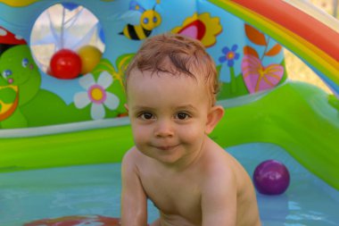 a boy having a bath in a plastic pool in the garden