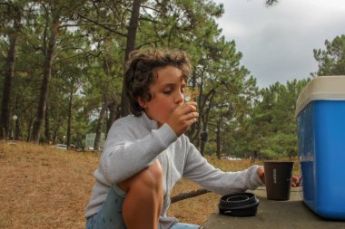 boy eating a healthy snack in a pine forest at the end of his vacation