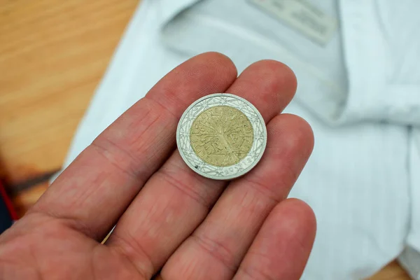 a two euro coin in the palm of my hand to pay for clothes