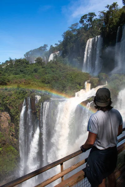 Sırtı iguazu şelalesine dönük genç bir adam.