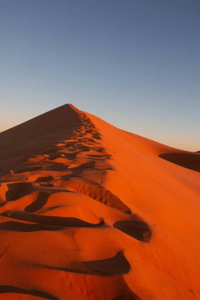 Gün batımında Sahara çölünde kum tepeleri, kumların üzerinde ayak izleri.