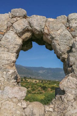 Türkiye 'nin antik Xanthos kentinin kalıntılarındaki kayalık bir kemerden mavi gökyüzüne sahip dağların inanılmaz manzarası.