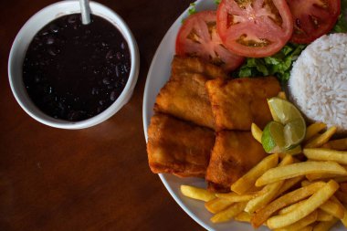 Tipik Brezilya kombinasyon tabağı, pirinç, kızarmış balık, patates kızartması, salata ve feijoada.. 