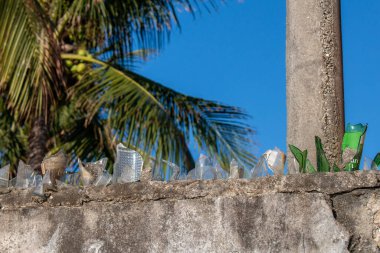 House wall with home security system with cut glass bottles in Sao Pedro da Aldeia, on a sunny day, Cabo Frio, Brazil.