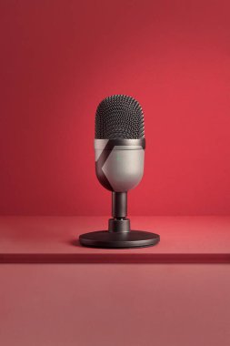 Renkli kırmızı bir zemin üzerinde dokuma ve kopyalama alanı olan özel bir tasarım mikrofonun minimalist ve modern görüntüsü. Teknoloji ve eğlence. Ürün ve ışıklandırma.