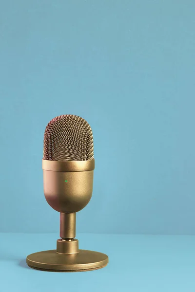 Elegant and luxuriously designed gold microphone for recording on a pastel-colored textured background with copy space. Contests and entertainment.