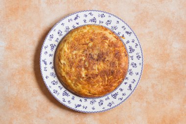 Genel bakış Geleneksel, ev yapımı İspanyol patates omleti Soyut pastel renkli stüdyo arka planında büyük dekoratif desenli bir tabak.