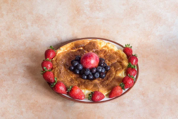 自家製のおいしいチーズケーキを中心に 抽象的なパステルカラーの背景に赤い梅とブルーベリーのイチゴで囲まれた丸皿 — ストック写真