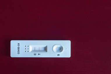 Covid-19 için pozitif bir hızlı antijen testi. Kopya alanı olan kırmızı ahşap bir masa üzerinde. Tıp ve Bilim.