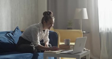 Öğrenci bilgisayarda video görüşmesi yapıyor ve not alıyor.