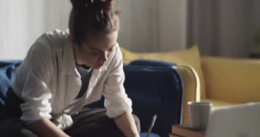 Odaklanmış kız öğrenci not alıyor ve ödev yapıyor.