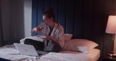 Yatakta film izleyen genç kadın.