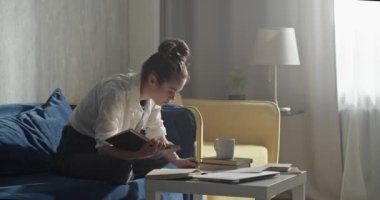 Öğrenci ödev yapıyor ve not defterine not alıyor.