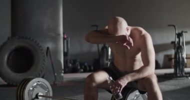 Ağırlık çalışmasından sonra yorgun sporcu su içiyor.