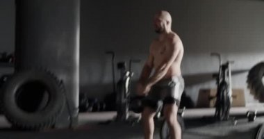 Spor salonunda kettlebell salıncakları yapan kaslı sporcu