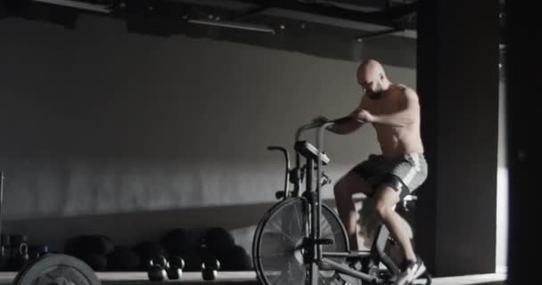 Sportsman exercising on air bike and doing clean and jerk — Stock Video