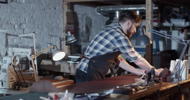 Мужчина ремесленник качения кожи в мастерской — стоковое видео