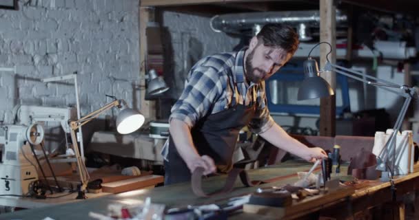 Ремесленник, работающий с кожей на рабочем столе — стоковое видео