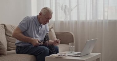 Doktora video çağrısında kan basıncını ölçen kıdemli hasta.