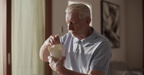 Senior Άνθρωπος Κάθεται Κοντά Στο Τραπέζι Και Τρώει Takeaway Τροφίμων — Αρχείο Βίντεο