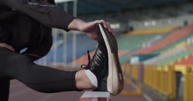 Sporcu antrenmandan önce öne doğru eğiliyor ve esniyor.