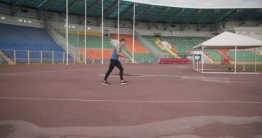 Genç atlet arenaya çıkıp barın üzerinden atlıyor.