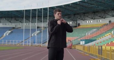 Genç sporcu antrenmandan önce fermuarını açıp eşofman ceketini çıkarıyor.