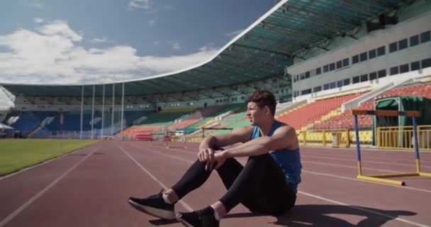 Yorgun Koşucu Antrenman Sırasında Pistte Oturup Nefes Alıyor — Stok video
