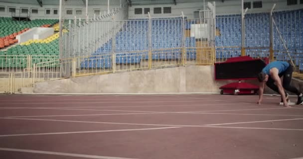 競技場の競馬場を走りながら障害物を飛び越えるスポーツマン — ストック動画
