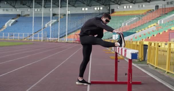 Sportsman Holding Leg Hurdle Stretching Workout Arena — ストック動画