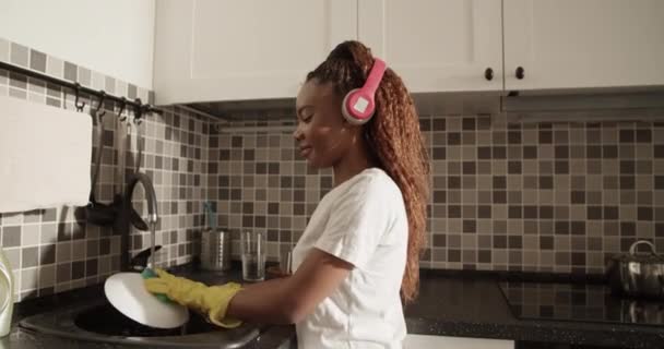 African American Woman Listening Music Washing Plate Home — Video