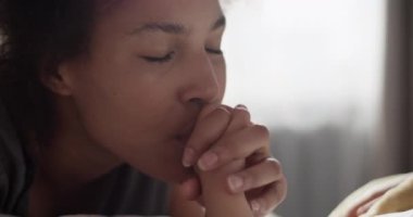 Neşeli siyah anne, sabah çocuğun eline dokunup öpüyor.