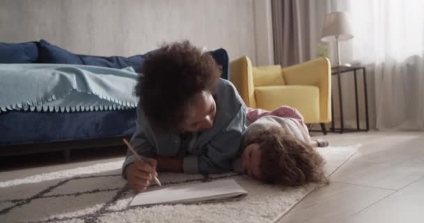 Czarny Mama Rysunek Rozmowa Dziecko Podczas Chilling Podłodze Pobliżu Sofa — Wideo stockowe