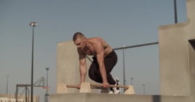 Spor sahasında amuda kalkma egzersizi yapan kaslı bir sporcu.