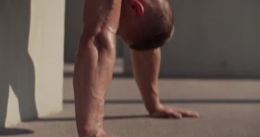 Sweaty male athlete doing handstand near concrete wall during workout