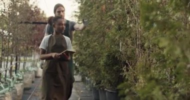 Multiracial male and female colleagues with tablet walking and checking plants during work in countryside