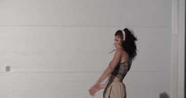 Genç bir kadının kablosuz kulaklıklarla müzik dinlerken ve modern şehrin sokaklarında dans ederken görüntülerini izliyoruz.