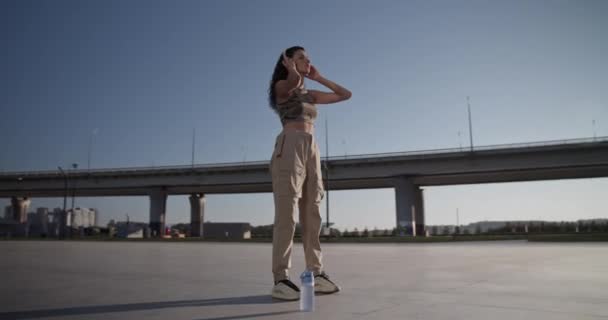 Düşük Açılı Genç Bayan Dansçı Gündelik Kıyafetlerle Kablosuz Kulaklıklara Dokunuyor — Stok video