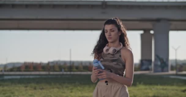 Відстеження Зйомок Жінки Повсякденному Одязі Пляшкою Води Прогулянки Вулиці Проти — стокове відео