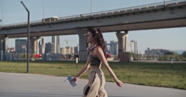 Tracking Shot Mujer Ropa Casual Llevando Botella Agua Caminando Por — Vídeos de Stock