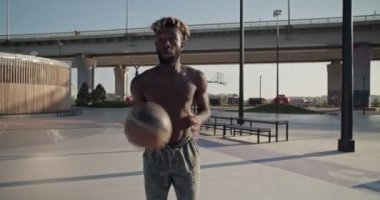 Üstsüz Afro-Amerikan sporcunun atladığı ve sokak topu antrenmanında atlayıp top attığı sahneyi yakınlardaki köprüde büyüt.