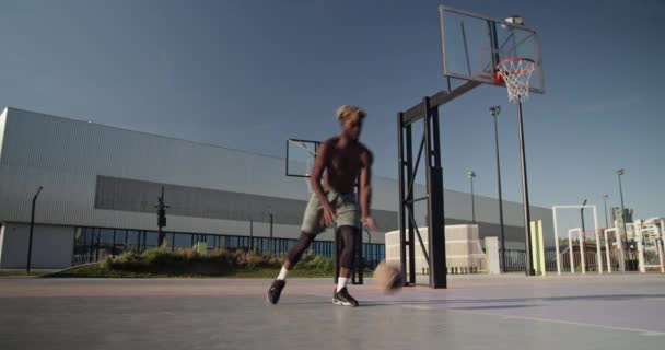 在城市的运动场上 年轻的黑人运动员在蓝天的天空下打篮球时 一动不动地冲向镜头和流口水 — 图库视频影像