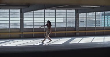 Ev içi boş park alanının içinde prova sırasında güneş ışığı altında performans gösteren kadın dansçının el kamerası görüntüsü.