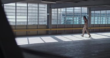 Ev içi boş park alanının içinde prova sırasında güneş ışığı altında performans gösteren kadın dansçının el kamerası görüntüsü.