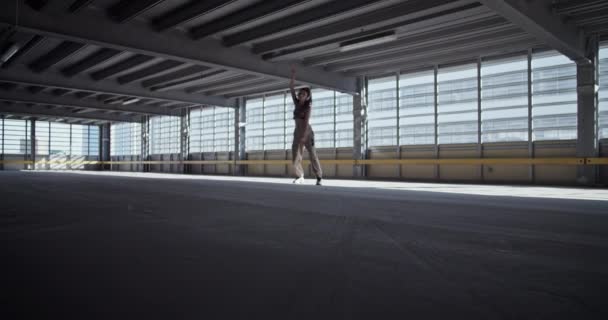 城市白天 穿着休闲装的女舞蹈演员在阳光充足的空旷停车场靠窗表演的静态镜头 — 图库视频影像